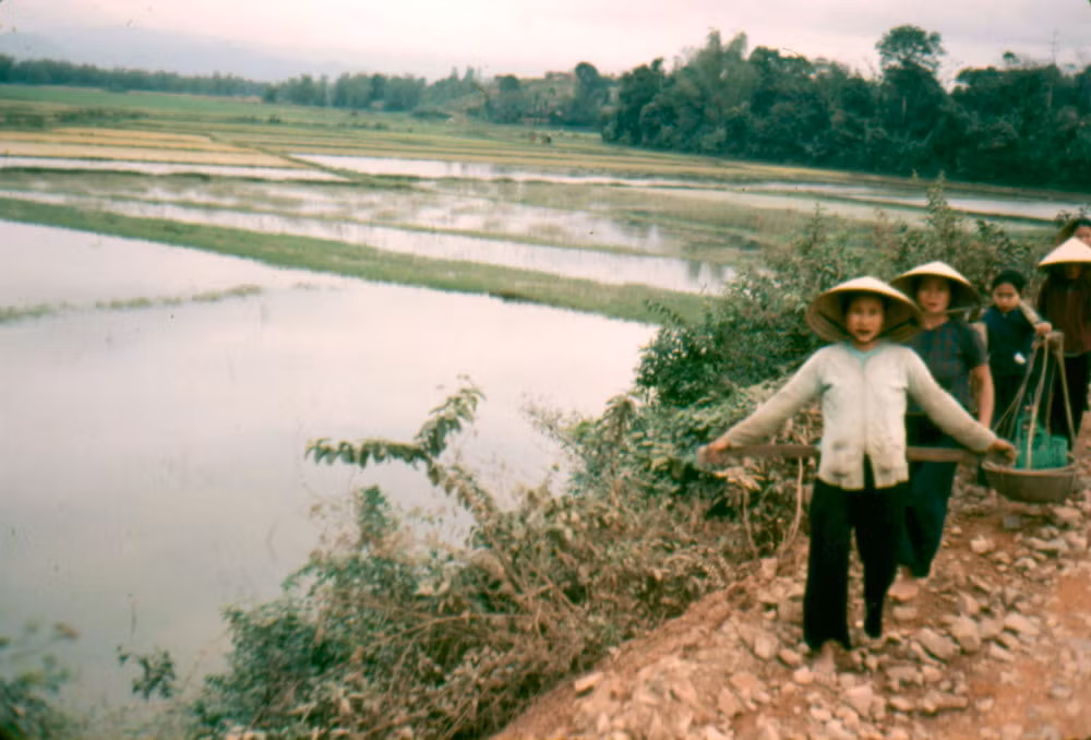 Những người phụ nữ chân đất bước đi trên con đường gạch đá lởm chởm.