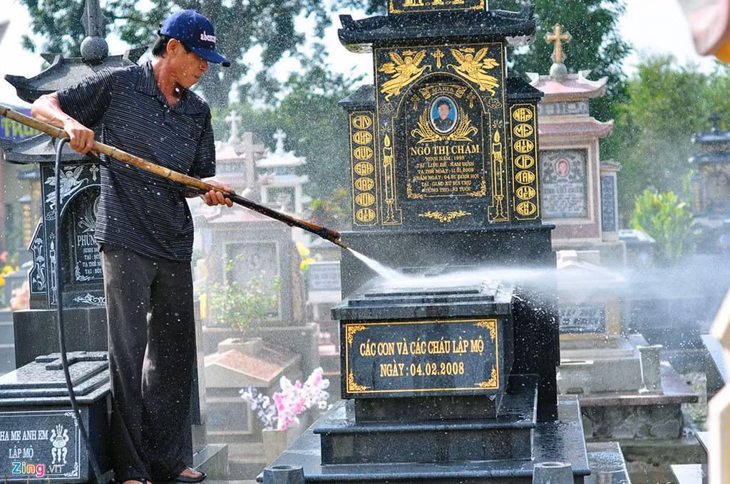 Nước rút chưa hết nhưng một người dân vẫn sử dụng máy bơm xịt rửa, làm sạch phần trên ngôi mộ.
