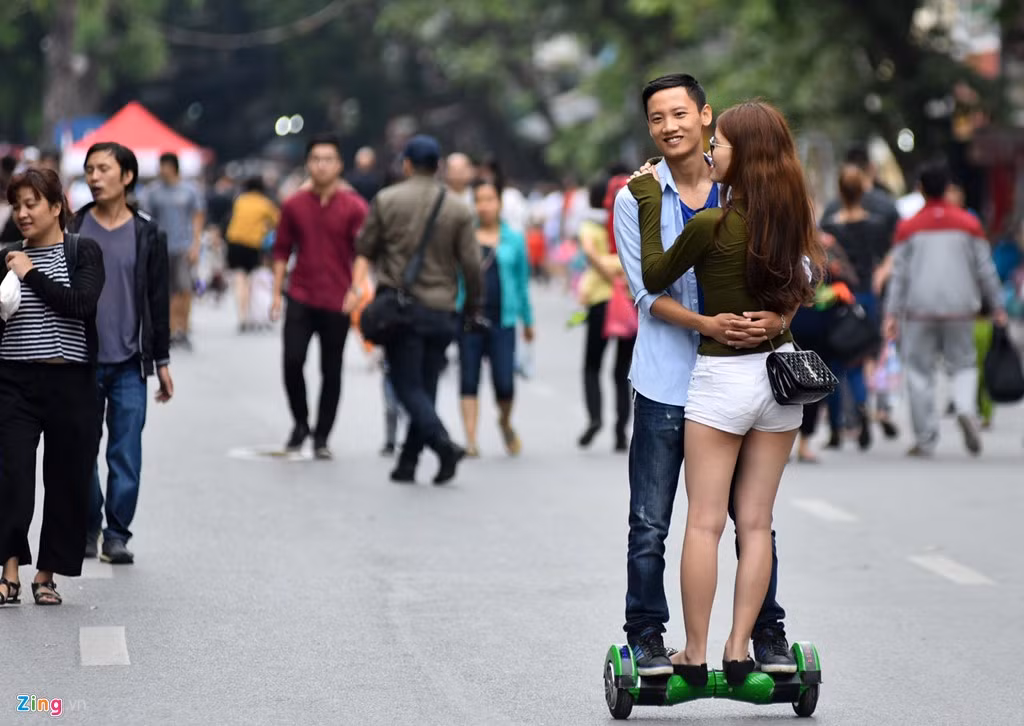 Đôi trai gái ôm nhau khi đi xe điện thăng bằng. Sau khi bị ngã khỏi xe do không kiểm soát được tốc độ, họ vẫn chơi tiếp theo cách như vậy.