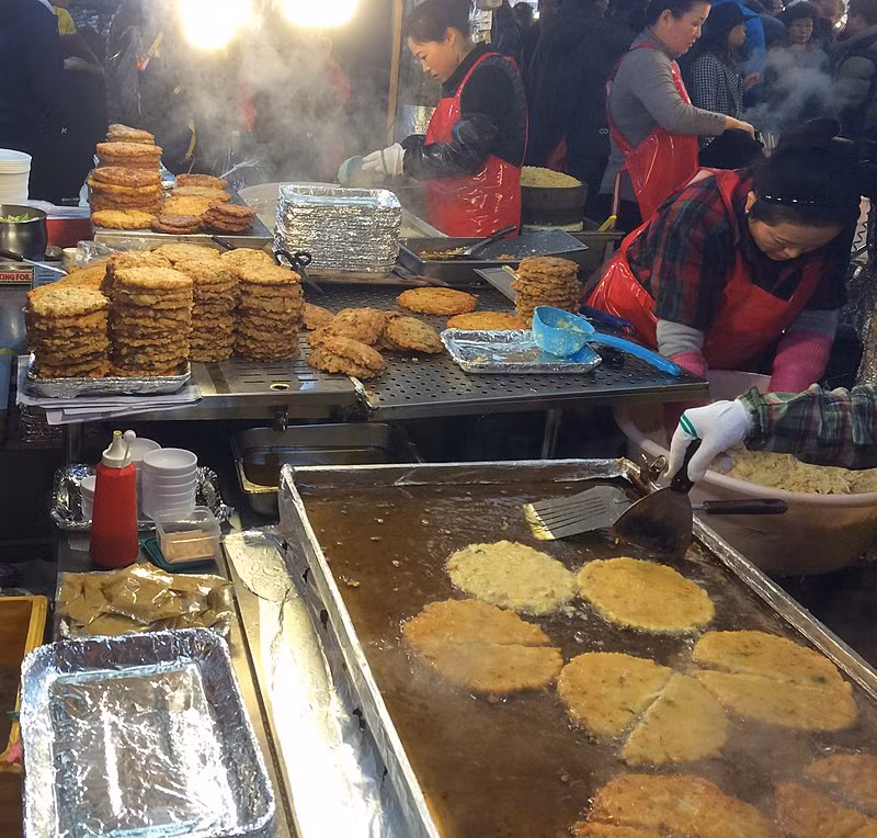 Những người bán hàng đang chiên bánh bindaetteok trong khu chợ. Ảnh: Wikipedia.