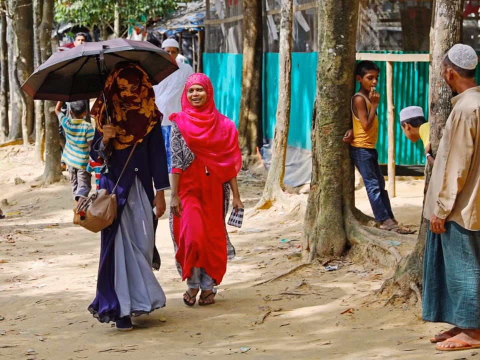 Theo một cuộc khảo sát năm 2015, Rakhine là bang có tỷ lệ biết chữ thấp nhất cũng như tỷ lệ đăng ký học tiểu học và cấp hai thấp nhất Myanmar. Ảnh: Formin đi cùng bạn, Shahima, qua một khu trại tị nạn ở Cox’s Bazar, Bangladesh, trước khi tới Chittagong để tiếp tục con đường học hành tại Đại học Phụ nữ Châu Á ngày 24/8/2018. 