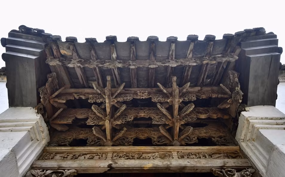 Hệ kết cấu gỗ dưới mái cổng uốn lượn theo hình cánh dơi của người Mông mang biểu tượng chữ “Phúc”. Ảnh: Zing