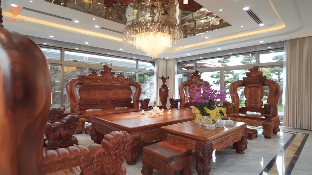 Trong phòng khách đặt bộ bàn ghế bằng gỗ hương nguyên khối lớn.