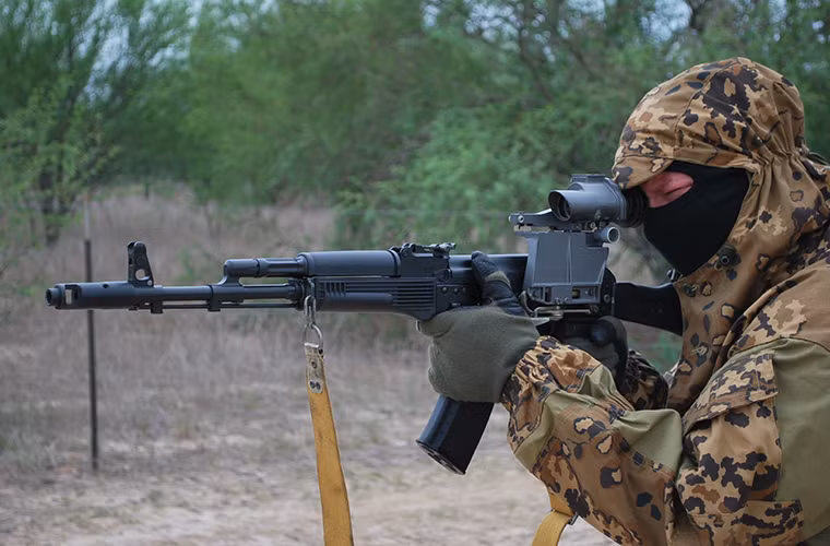 Kể từ năm 1991, AK-74M trở thành mẫu súng trường tấn công tiêu chuẩn của Quân đội Liên Xô và sau đó là Quân đội Nga. Bản thân biến thể này sở hữu các cải tiến rất đáng chú ý cho phép nó có thể phục vụ lâu dài trong Quân đội Nga thêm nhiều thập kỷ nữa trước khi một mẫu súng trường tấn công tương lai khác ra đời. Trong ảnh là một binh sĩ Nga với AK-74M có màu đen đặc trưng kết hợp với ống ngắm quang học 1P29. Nguồn ảnh: RussianOptics.net.