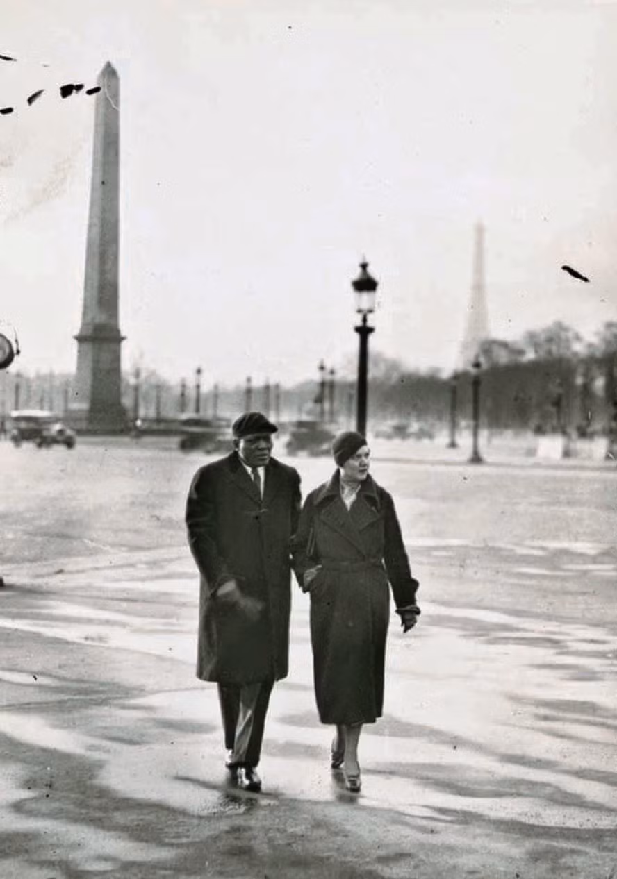 Võ sĩ quyền Anh người Mỹ Jack Johnson sánh bước đi bộ bên người vợ thứ hai Irene Pineau ở Paris, Pháp năm 1930.