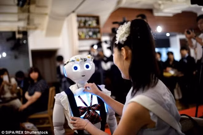 Một người phụ nữ đang chỉnh trang phục và điều khiển robot.