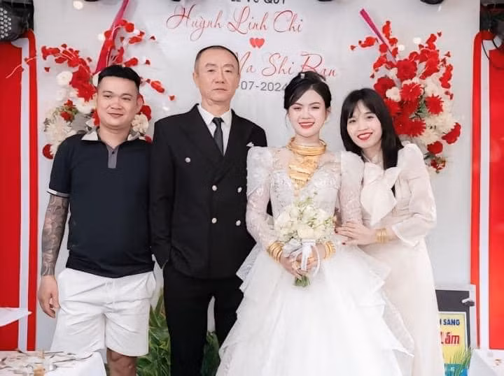Cô dâu sánh đôi bên chú rể với nụ cười rạng rỡ. Điều khiến nhiều người chú ý là nàng dâu trẻ tuổi đeo rất nhiều vòng - kiềng và nhẫn vàng. Trên cổ, cô đeo chừng 5 chiếc kiềng cỡ lớn, thêm một vòng cổ vàng với thiết kế hoa văn vô cùng tinh xảo và hiện đại. Còn 2 cô tay đeo chật lắc vàng, các ngón tay chi chít nhẫn.