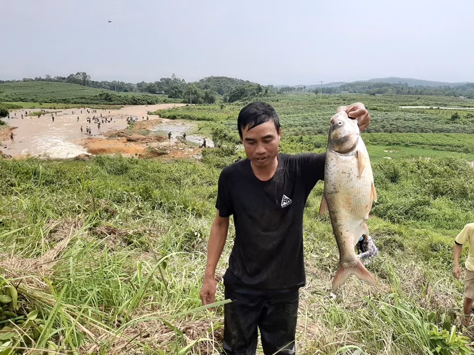 Người đàn ông và cá bắt được sau sự cố vỡ đập.