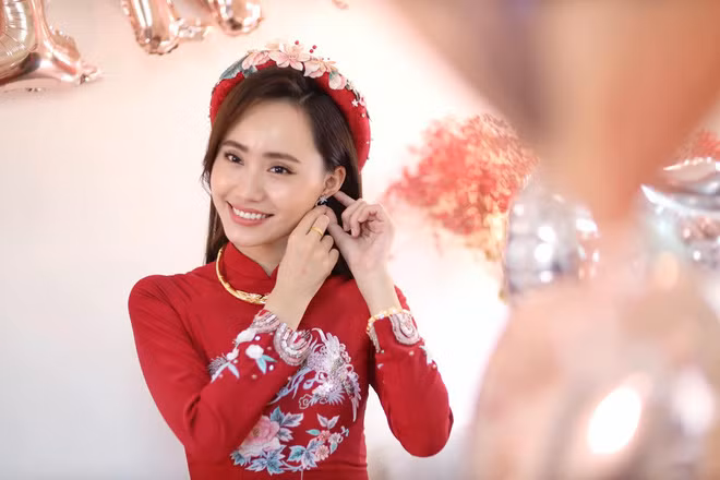 Trong lễ ăn hỏi, Xuân Anh diện mẫu áo dài đỏ với hình thêu nổi bật. Cô để tóc dài xõa và đội chiếc mấn đính hoa cầu kỳ.