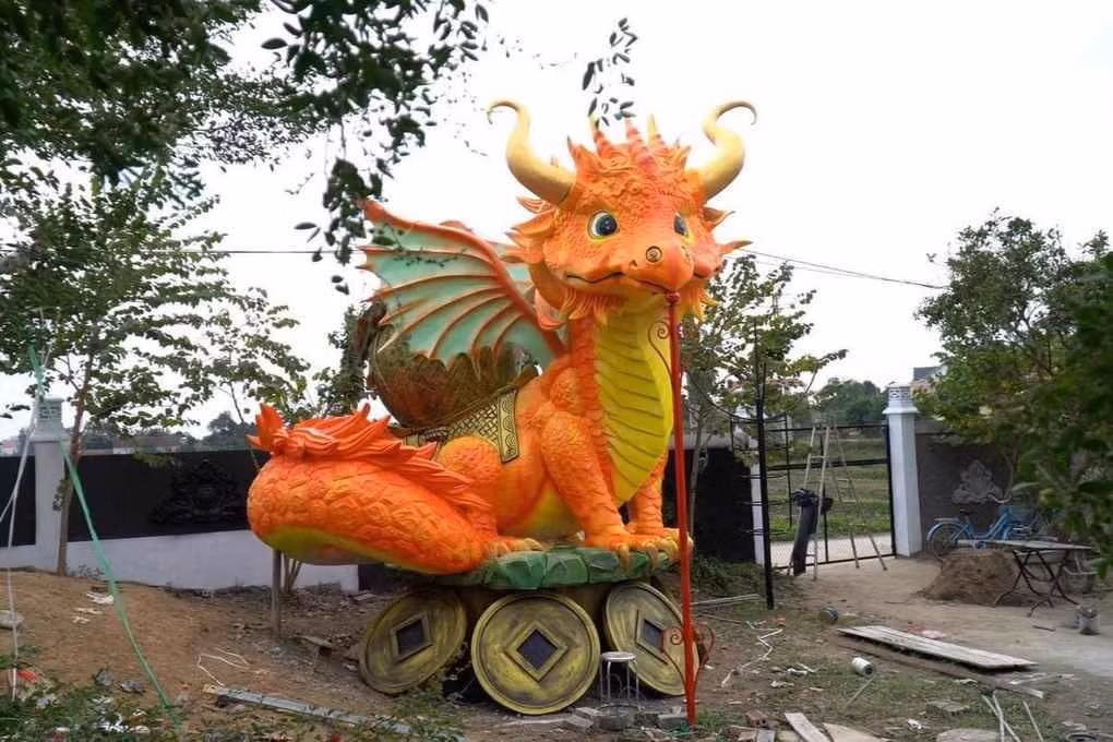 Chú rồng với màu cam và vàng chủ đạo. Bên dưới chú rồng còn có bệ đỡ được tạo hình đồng tiền mang ý nghĩa thiết thực trong năm mới này.