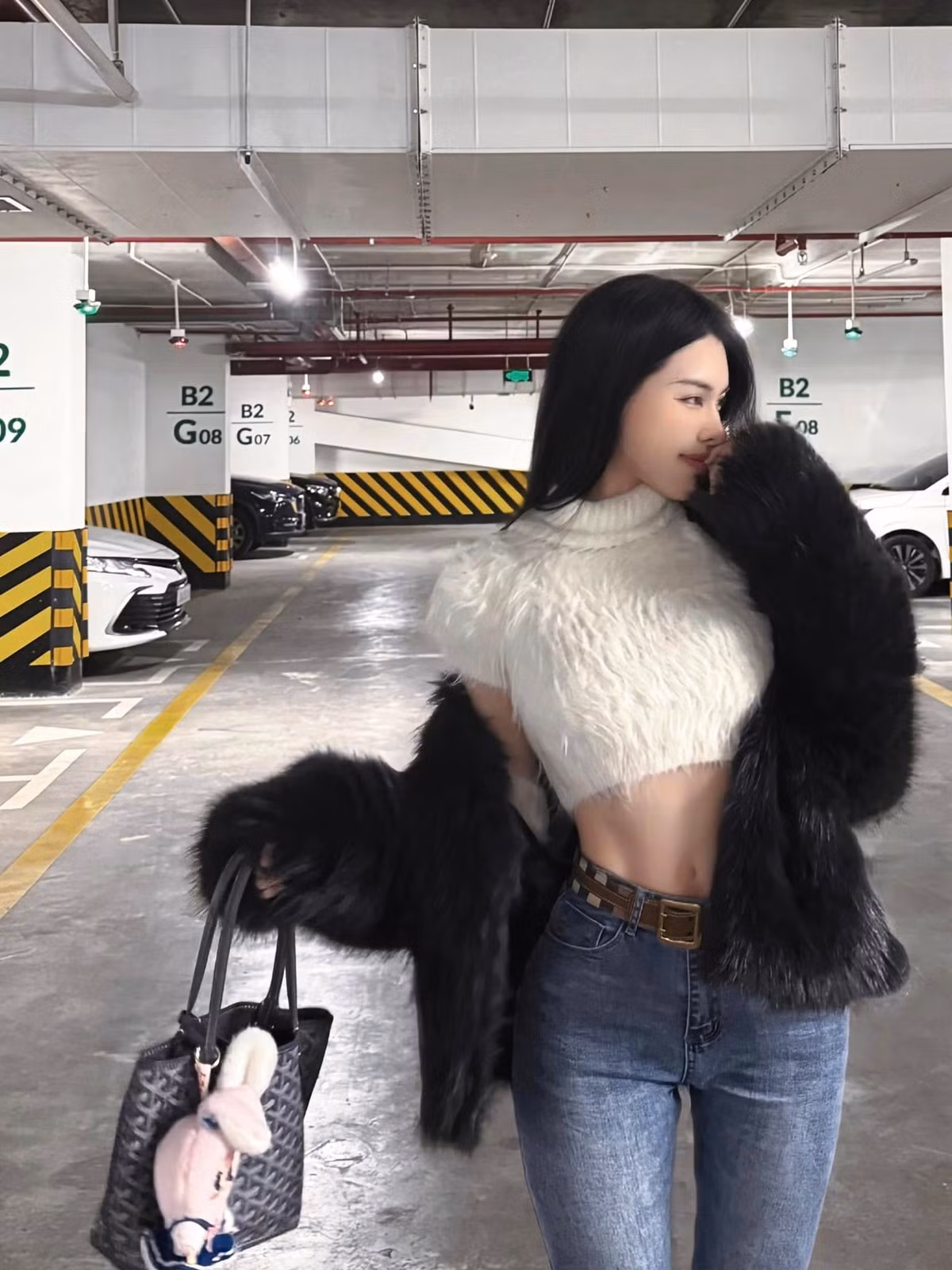 Bạn gái Văn Thanh xuất hiện với outfit thời thượng gồm áo crop top đính lông vũ màu trắng, quần jeans xanh bạc màu ôm sát, dây lưng da bò sành điệu.