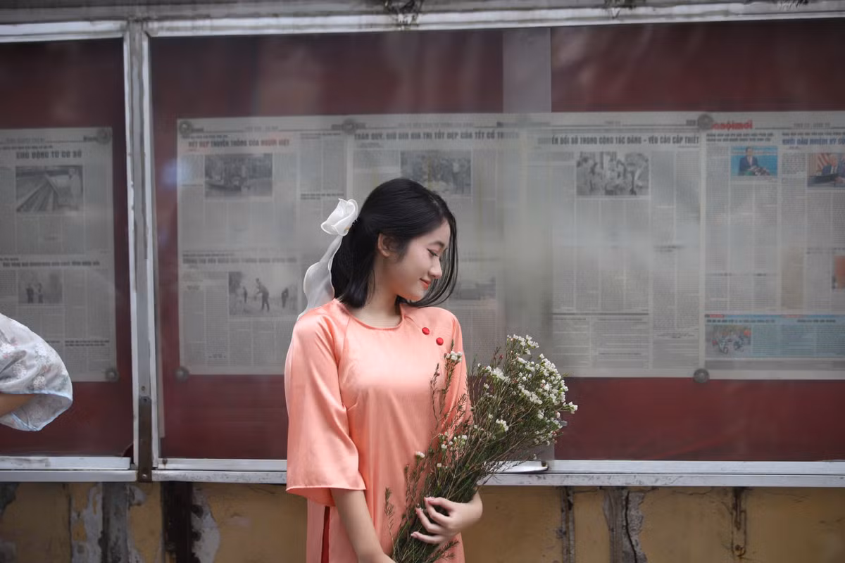 Vô vàn các nàng thơ tranh thủ diện áo dài, chụp ảnh trước bảng tin báo Hà Nội mới.