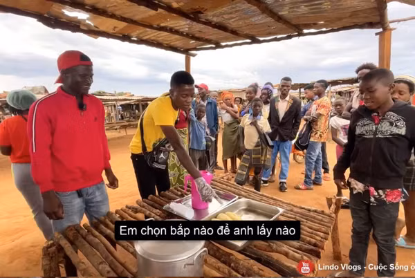 Lindo làm nhiệm vụ gói ngô cho khách, còn một anh chàng nữa thì hỗ trợ Youtuber rót nước ngô tặng mọi người.