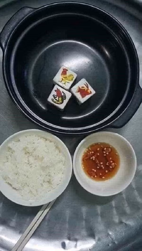 Thay vì đuề huề thịt cá thì anh thanh niên lại khoe mâm cơm chỉ có bát cơm trắng, chén nước mắm và thứ bên trong nồi là "tôm cua cá" đủ cả nhưng lại bằng giấy.