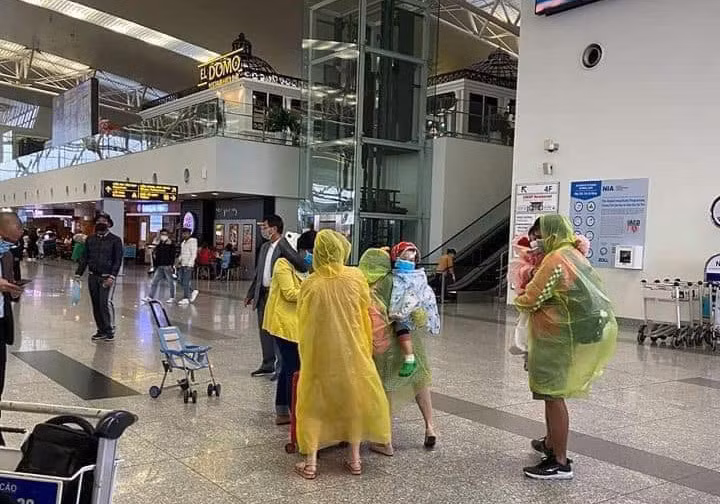 Một gia đình trùm áo mưa trong sân bay