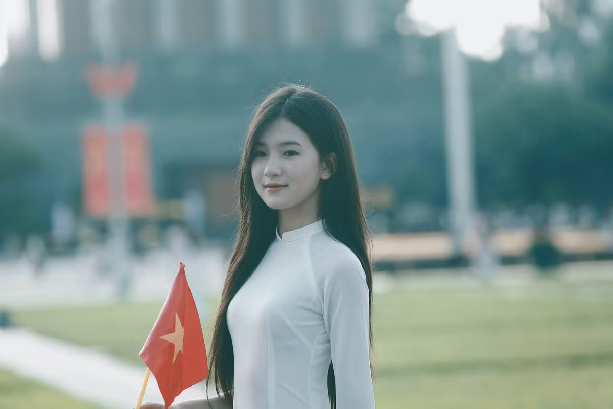 Thiếu nữ xúng xính trong bộ áo dài cùng cờ đỏ sao vàng chụp ảnh trước Quảng trường Ba Đình.