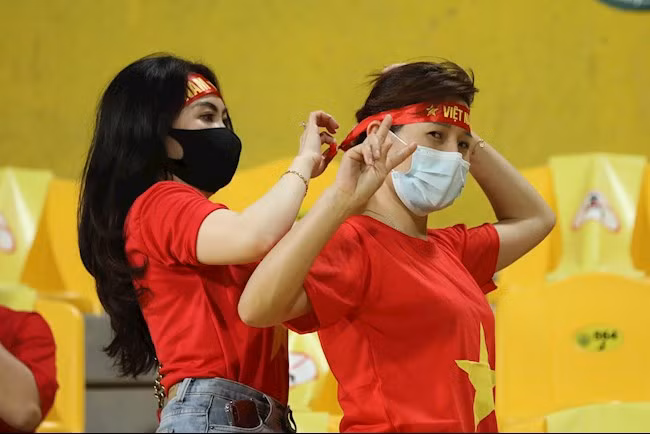 2 nữ CĐV đã giúp nhau thắt chặt tấm băng đô để cổ vũ đội tuyển Việt Nam.