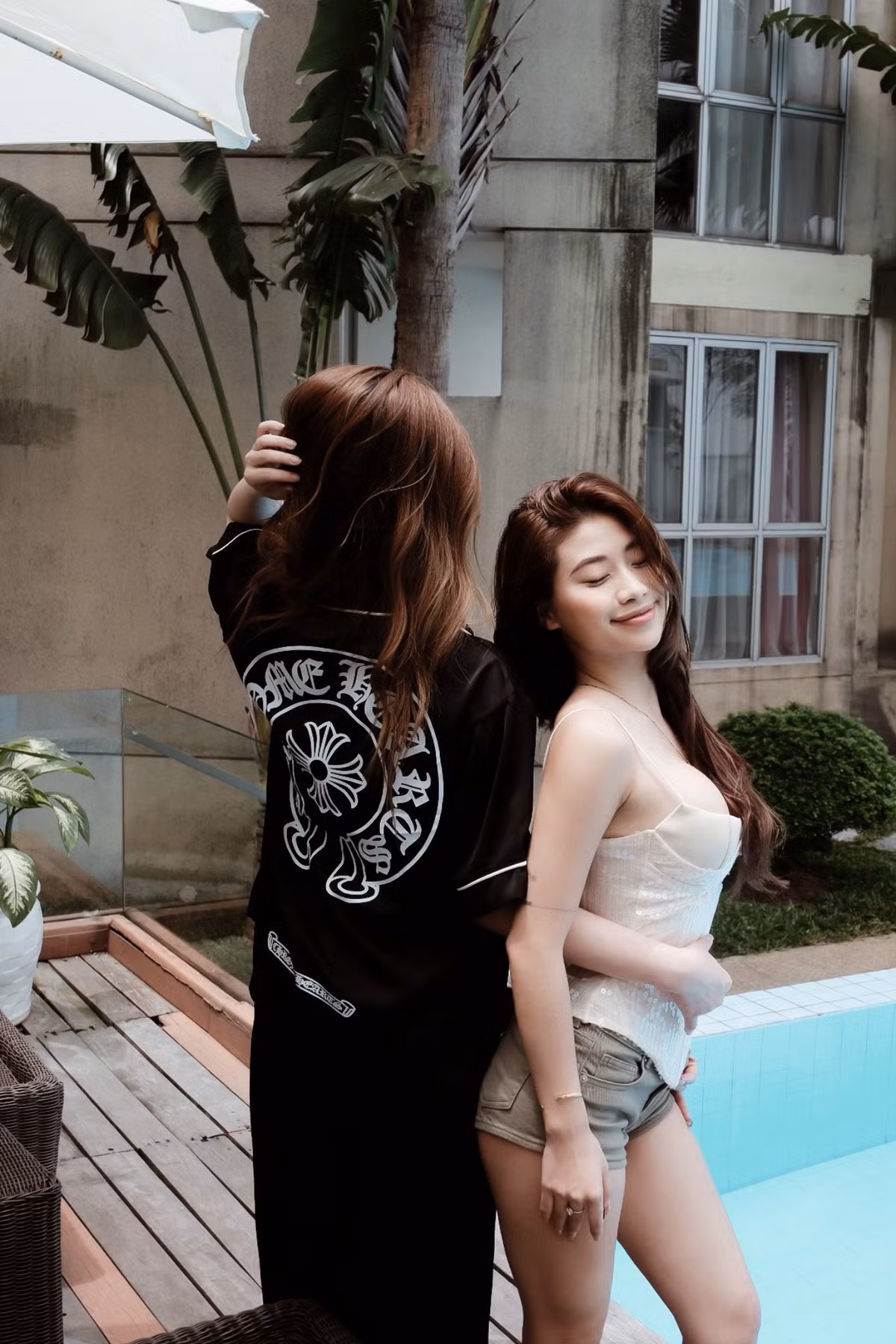 Chiếc áo tắm với phần áo có nút thắt phía trước tôn lên vòng một đầy đặn. Mái tóc dài màu nâu sẫm, để xõa tự nhiên, bay nhẹ trong gió, tạo cảm giác năng động.