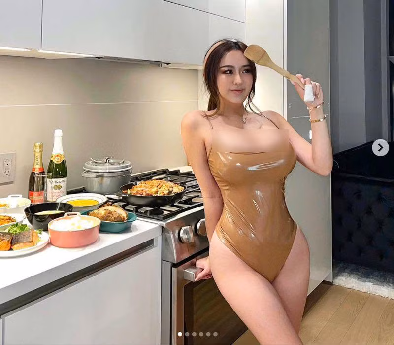 Mới đây, Rebecca gây chú ý khi diện bodysuit vào bếp, khoe trọn thân hình đầy đặn. Bộ trang phục có tông màu nude, kiểu dáng 1 mảnh tối giản với chất liệu nhựa vinyl bóng bẩy, phô từng đường nét cơ thể.