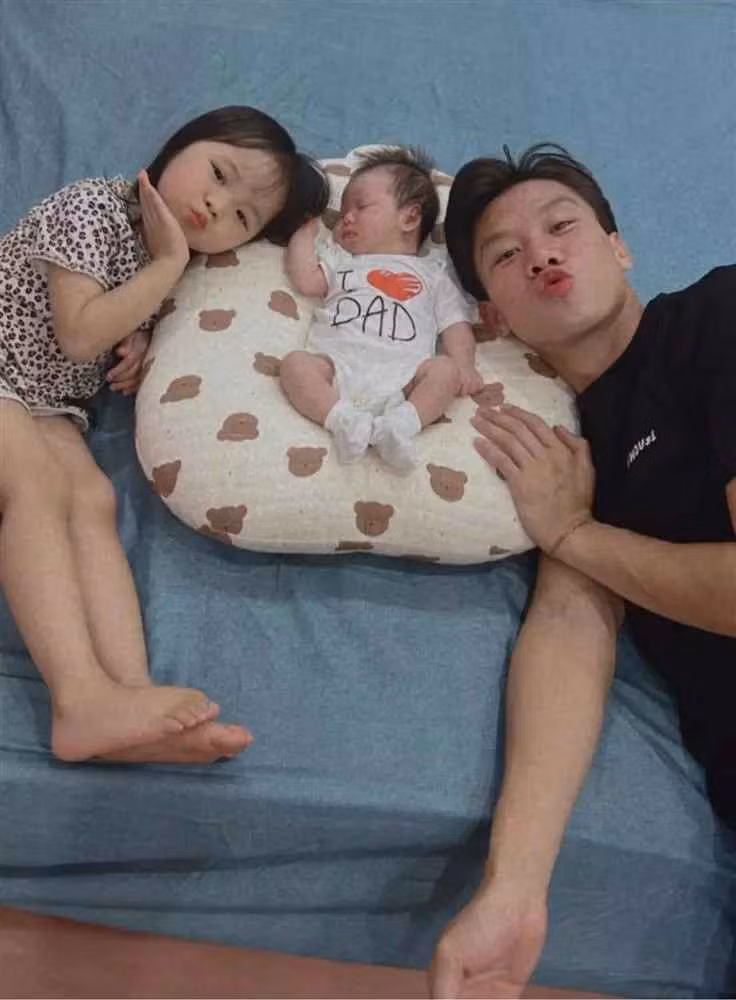 Theo đó, hậu vệ đội tuyển Việt Nam diện quần áo giản dị, đầu tóc rối bời, phụ vợ chăm ru con gái thứ 2 ngủ.