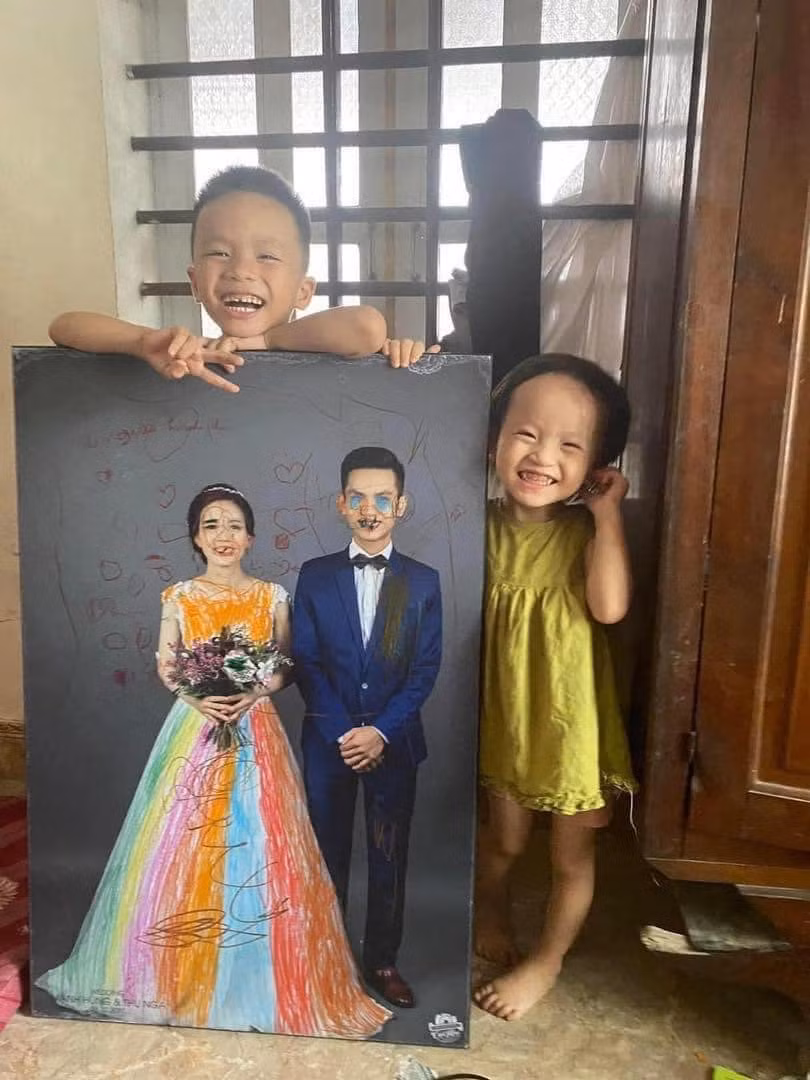 Cụ thể, tấm ảnh cưới của cặp vợ chồng trẻ đã được các con đem ra tô màu với những đường nét nghệch ngoạc và khi bắt được "thủ phạm", cả 2 cùng đứng chụp ảnh với tác phẩm.