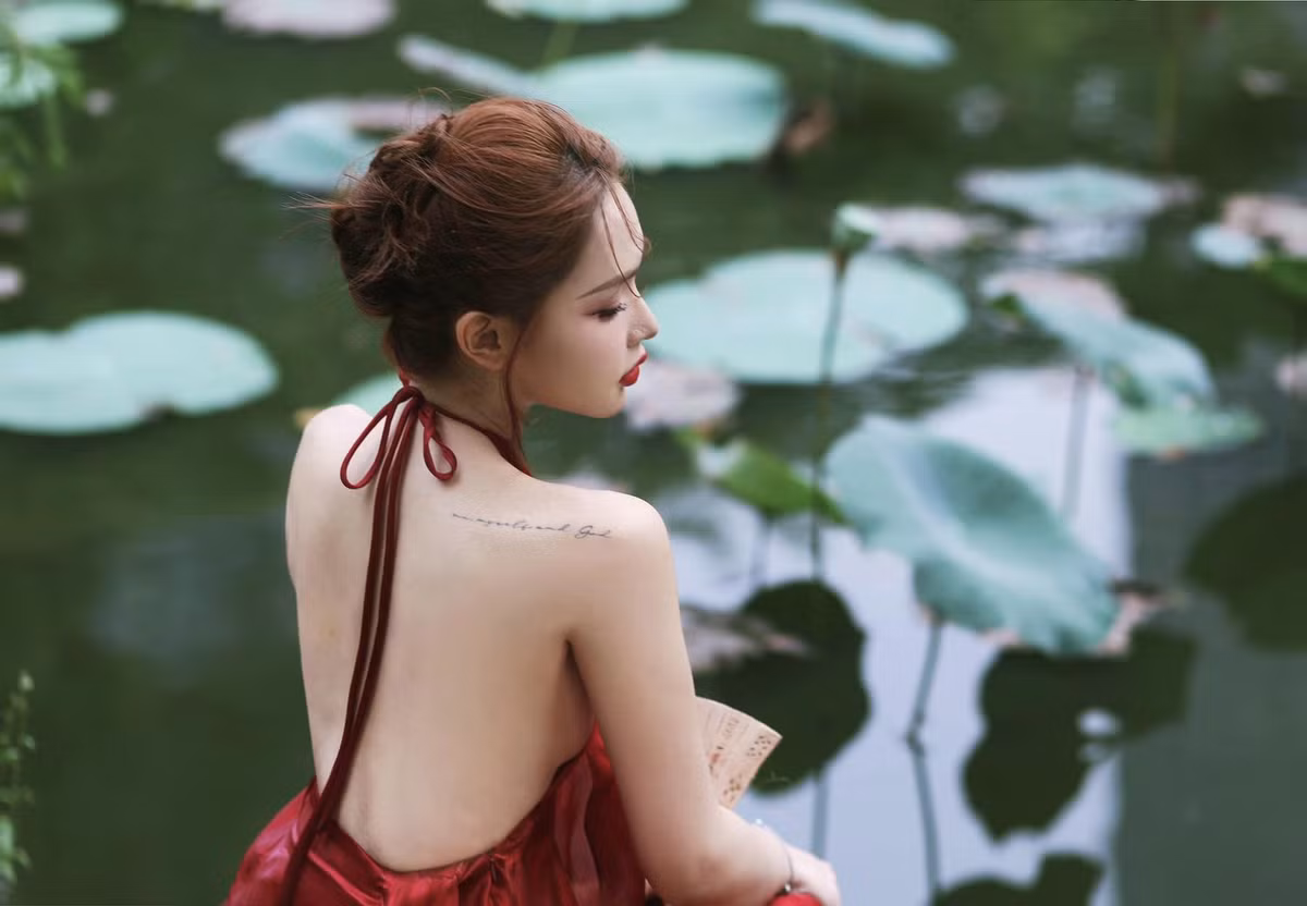 Người đẹp chuyển giới hoàn thiện vẻ ngoài với cách make up nhấn chủ yếu vào phần mắt và môi dùng son đỏ đậm, búi tóc cao, tay cầm quạt xếp nan tre.