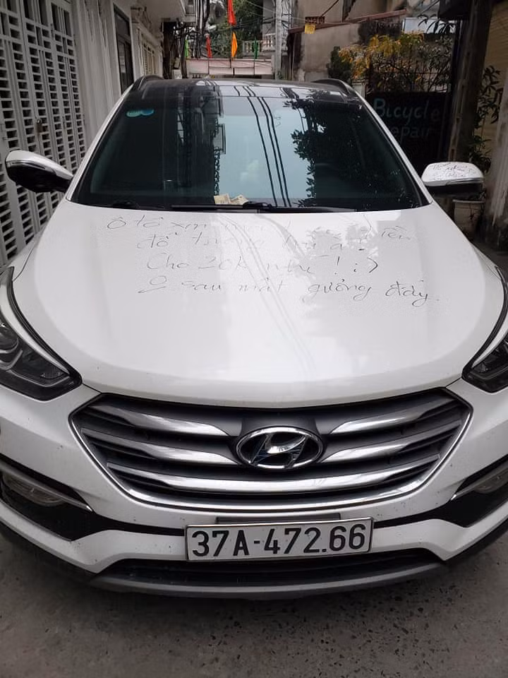 Trên nắp xe ô tô màu trắng đã bị chủ nhà ghi dòng chữ: "Ô tô xịn mà không có tiền gửi trong bãi à? Cho 20K nhé! Không sau mất gương đấy".