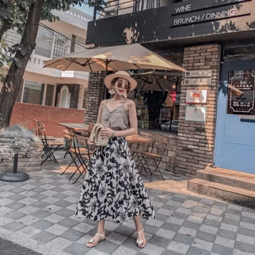 Áo hai dây và chân váy xòe luôn là bộ đôi hoàn hảo được nhiều quý cô lựa chọn trong những ngày hè oi bức. Để set đồ không nhàm chán, bạn có thể phối thêm phụ kiện cơ bản, đặc trưng của mùa hè như mũ cói, kính mắt và sandals đế bệt.