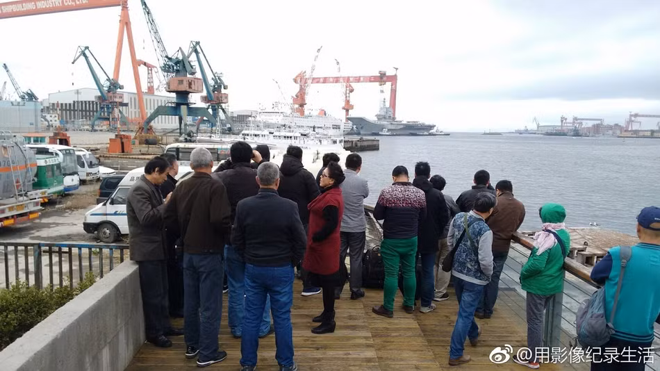 Khoảng 10h sáng ngày 23/4, tàu sân bay Type-001A đã được các tàu lai dắt kéo ra khỏi vị trí neo đậu ở cầu cảng. Một số người dân sống gần cảng Đại Liên tập trung xem tàu sân bay nội địa đầu tiên của Trung Quốc rời cảng, chuẩn bị thử nghiệm. Ảnh: Sina.