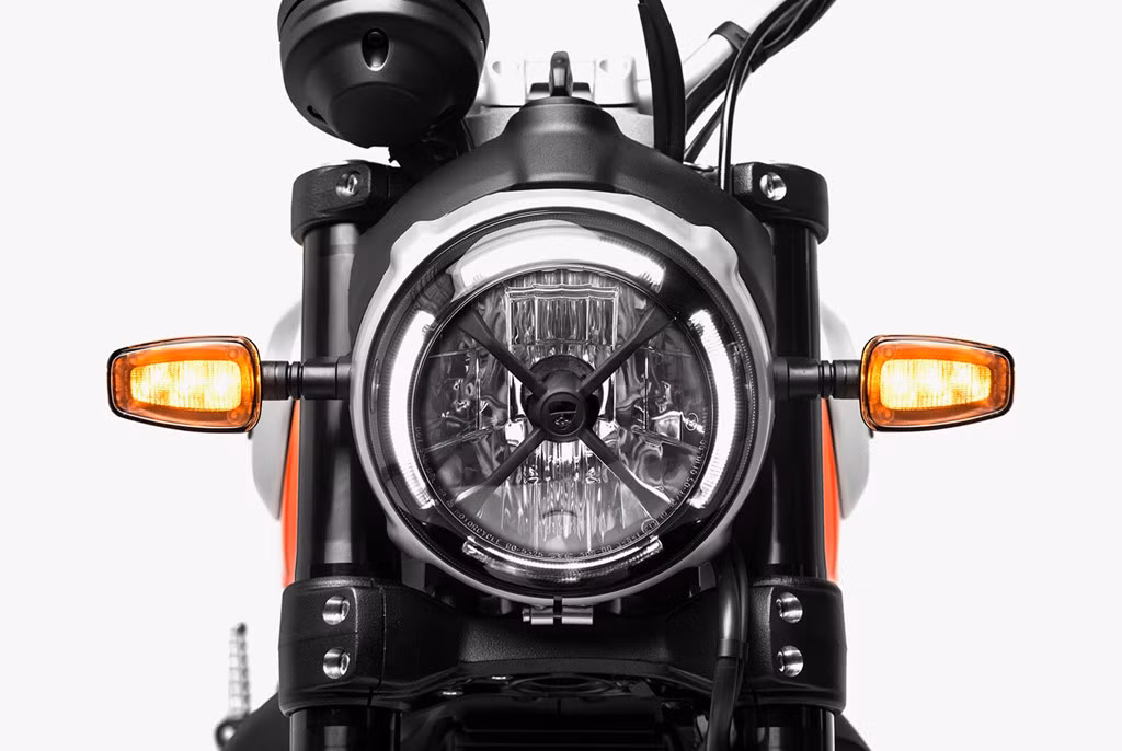 Thay đổi ở hệ thống đèn chiếu sáng trên Scrambler 2019 là điểm dễ nhận ra nhất. Bên cạnh đèn pha được mạ chrome bên ngoài, xe còn sở hữu thêm đèn LED định vị được bố trí viền tròn theo chóa đèn pha đi kèm khung chữ X màu đen lấy cảm hứng từ những mẫu xe đua ở thập niên 1970. Đèn xi-nhan cũng được thay bằng đèn công nghệ LED.
