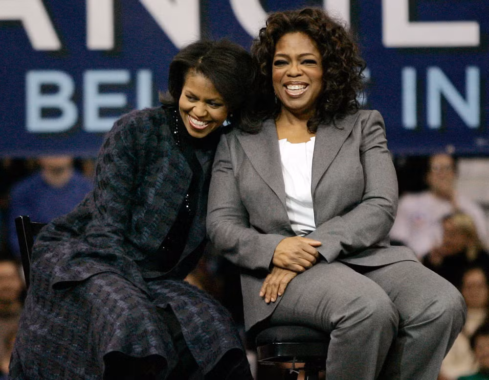 Bà Michelle Obama, phu nhân của cựu Tổng thống Mỹ Obama, cười tươi khi ngồi cạnh người dẫn chương trình truyền hình Oprah Winfrey tại Manchester ngày 9/12/2007.