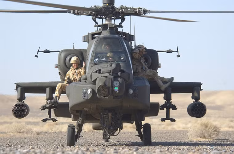 Một buổi huấn luyện tình huấn sơ tán khẩn cấp với một chiếc AH-64 Apache của Không quân Hoàng gia Anh cùng hai binh sĩ hai bên thân máy bay.