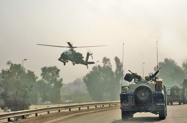 Một chiếc AH-64 Apache hộ tống đoàn xe cơ giới thuộc Lữ đoàn chiến đấu số 3 thuộc Quân đội Mỹ trên đường đến thành phố Fallujah, Iraq, khi thành phố này bị các tay súng nổi dậy chiếm giữ.