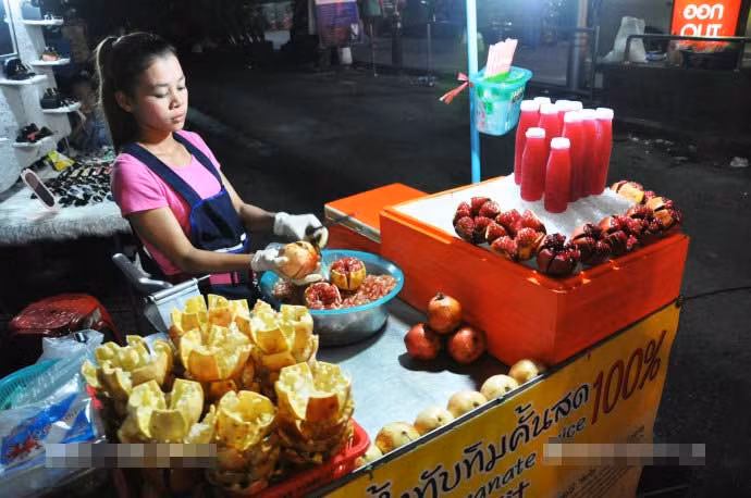 Đoàn khách Trung Quốc đã ghi lại hình ảnh về cuộc sống thường nhật ở thành phố Bangkok trong chuyến đi vào đầu năm 2017. Ở đó, những xe bán hàng rong xuất hiện trên các con phố ở trung tâm Bangkok, góp phần tạo thêm một hình ảnh rất riêng của quốc gia Đông Nam Á này. Ảnh: Cô chủ sạp bán hàng rong đang tách quả lựu ra để làm đồ uống hoặc bán cho khách. Ảnh Sina