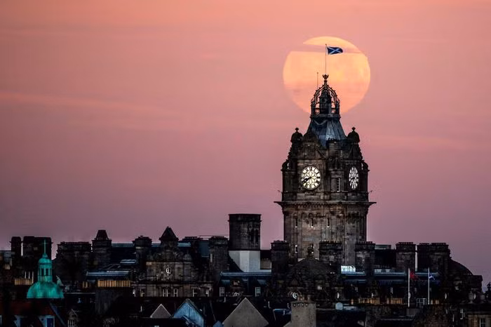 Trăng Sói dần lặn sau tháp đồng hồ Balmoral ở Edinburgh.