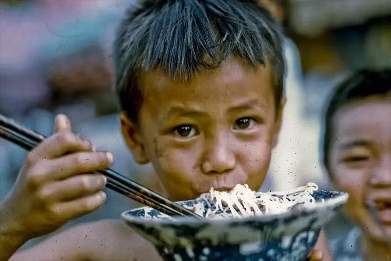 Em bé đang ăn bún với đôi mắt long lanh.