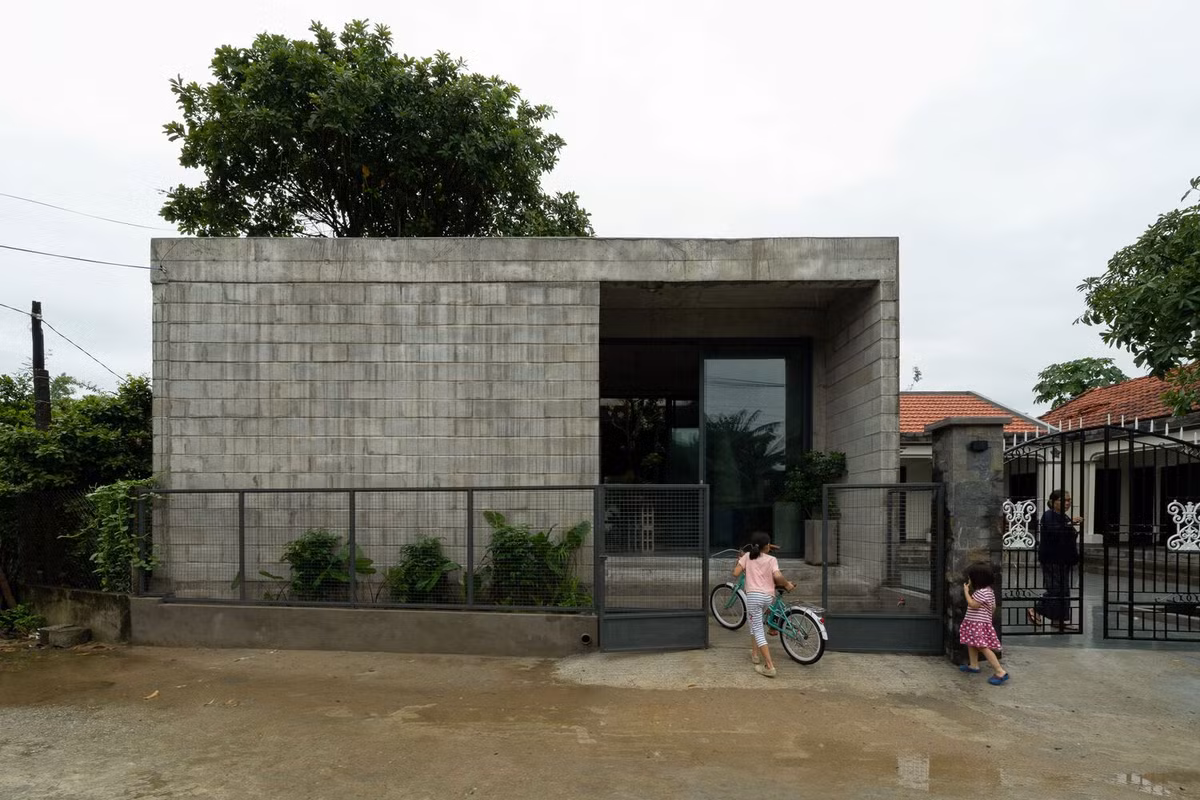 Lối vào chính được bố trí để đảm bảo sự riêng tư, với bức tường khối bê tông chưa hoàn thiện và cửa kính lõm tạo sự tách biệt khỏi đường phố nhưng vẫn duy trì tầm nhìn từ bên trong. Ảnh: Quang Trần