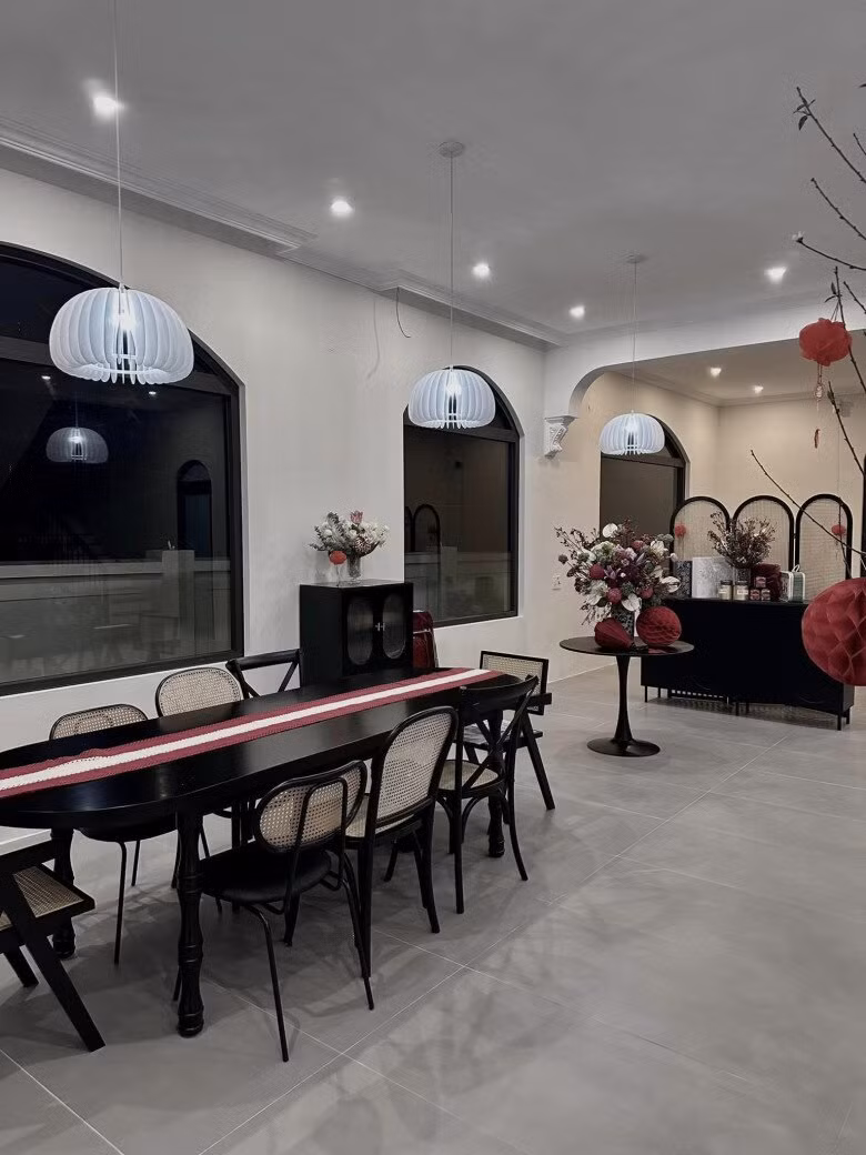 Bàn ăn dài bằng gỗ đen được trang trí bởi đèn treo hiện đại. Ảnh: FBNV