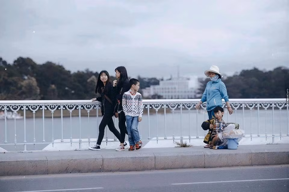 Sự xuất hiện vô tình của mộ cậu bé có điều kiện sống khá đủ đầy, ăn mặc đẹp, đi cùng người thân ngang qua chỗ cậu bé bán hàng rong đã tạo nên sự đối lập, tương phản kích thích người xem phải suy ngẫm. Cùng là trẻ em nhưng hai bạn nhỏ này lại có hai cuộc sống, số phận hoàn toàn khác nhau. Ngoài ra, bộ ảnh còn hiện lên thực trạng thờ ơ, vô cảm của số đông người đi đường khi chứng kiến hình ảnh đáng thương của cậu bé. Ảnh: Lê Quang Long.