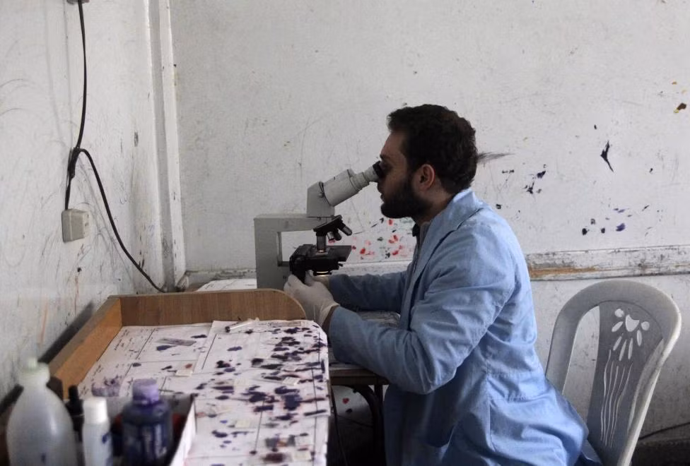 Nhân viên phòng xét nghiệm đang kiểm tra mẫu máu cho bệnh nhân tại một bệnh viện ở thành phố Aleppo.