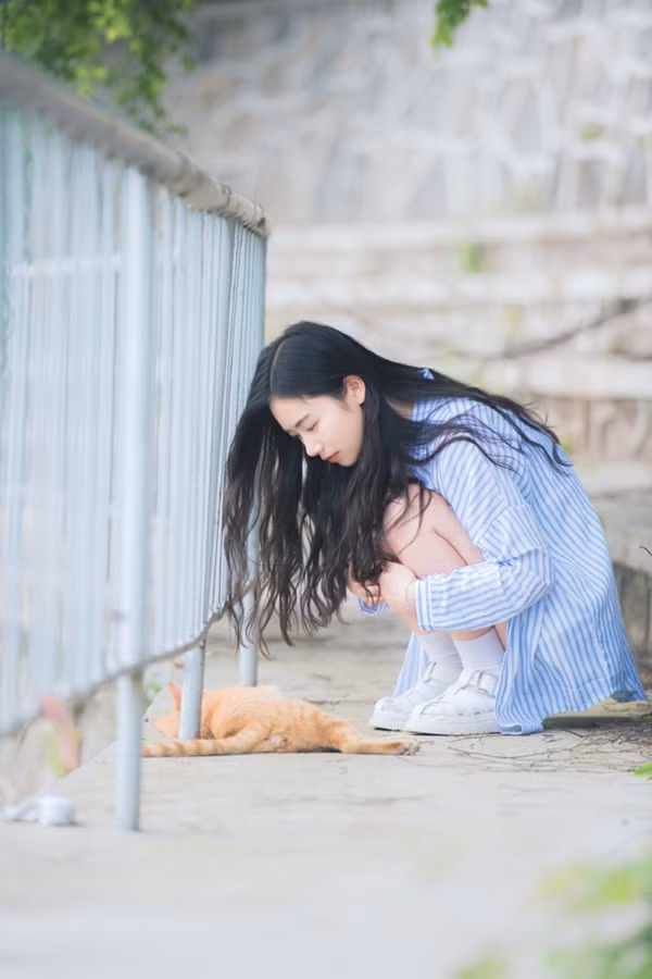 Hu Anru chơi đùa với một chú mèo ở góc sân trường.