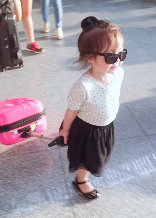 Bé Mộc Trà còn tự tin kéo chiếc vali màu hồng dễ thương khiến nhiều người thích thú. (Ảnh: Facebook Elly Trần)