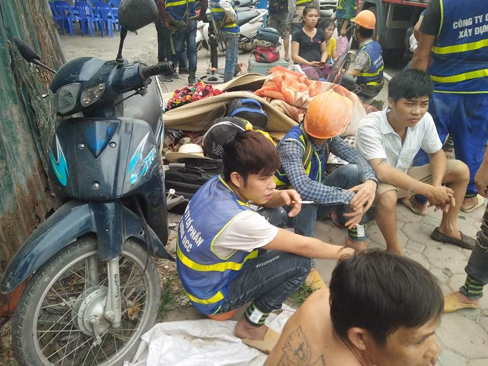Nhiều công nhân ngồi tụ tập bên đường theo dõi việc chữa cháy.