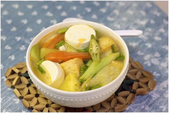 Đầu tiên, đun nóng một ít dầu ăn, phi đầu hành thơm, cho cà chua vào xào chín, xào khoảng 3 phút thì cho tiếp dứa vào xào cùng, nêm vào một ít muối, đường.Thêm nước lọc vào và đun sôi sau đó thả me vào. Đun từ 10 đến 12 phút thì cho tiếp đậu bắp vào đun cùng, đun khoảng thêm 5 phút và cho đậu vào. Thêm hành ngò để nồi canh thêm dậy mùi. Ảnh: Hoidaubepaau.