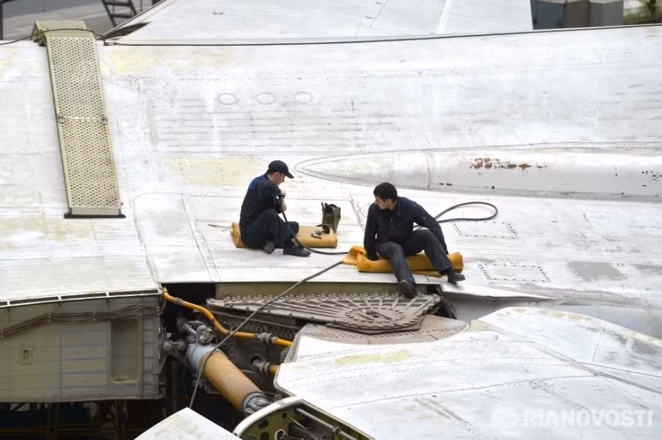 Hai công nhân đang làm việc bên cạnh cơ cấu khớp kéo "cánh cụp, cánh xòe" của chiếc Tu-160. Cơ chế cánh cụp cánh xòe giúp máy bay đạt được trọng lượng cất cánh lớn hơn và khoảng cách bay cũng như vận tốc cao hơn so với các loại cánh bằng đơn thuần. Tuy nhiên nó cũng khiến việc bảo dưỡng trở nên khó khăn hơn và cũng là nguyên nhân làm giảm tuổi thọ sử dụng của máy bay. Nguồn ảnh: RIA Novosti