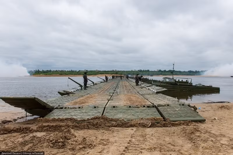 Tất cả các xuống máy và thiết giáp lưỡng cư chỉ tập trung ở một bên cầu phao, phía đối diện dòng nước để "đẩy" các đốt cầu phao theo ngược hướng dòng nước giúp chúng không bị nước cuốn, bẻ cong. Nguồn ảnh: Englishrussia.