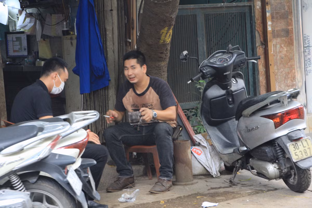 Nam thanh niên không đeo khẩu trang, uống nước, phì phèo điếu thuốc và trò chuyện với bạn ở ngoài đường La Thành (quận Đống Đa) như chưa hề có quy định giãn cách xã hội.