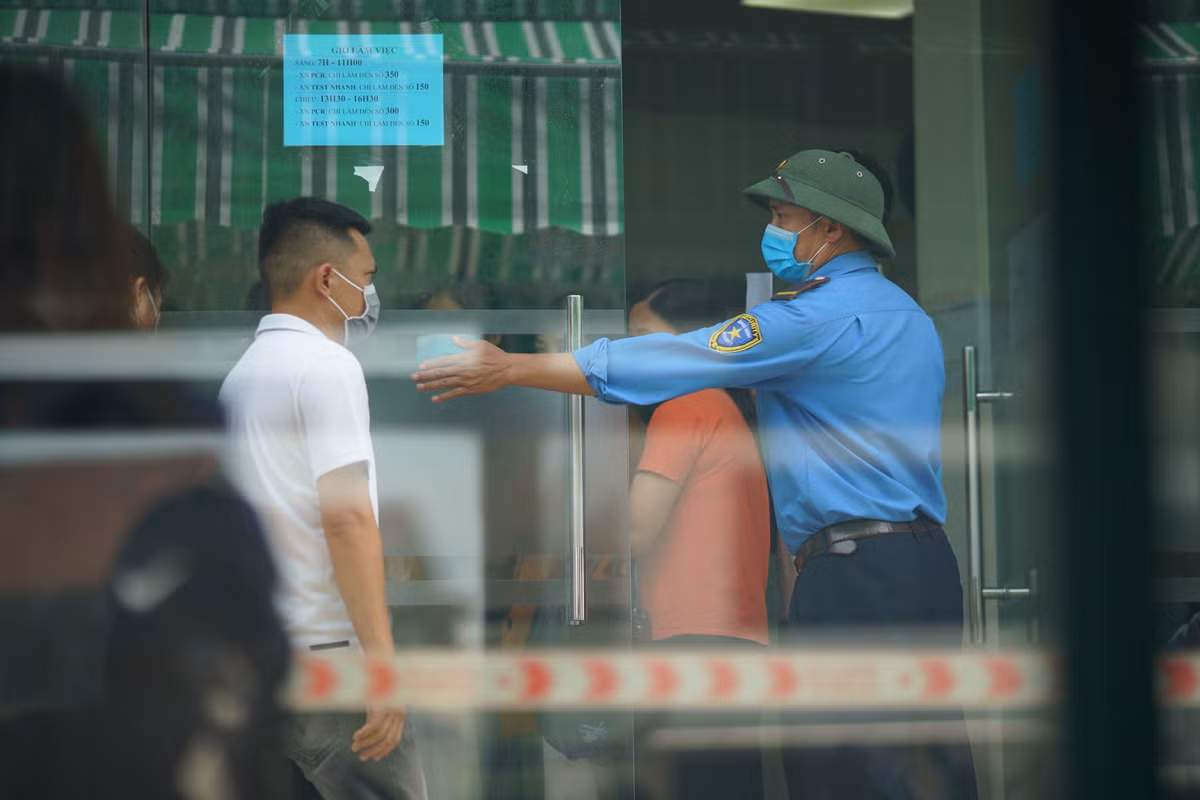 Nhân viên trung tâm xét nghiệm đã rất vất vả hướng dẫn người dân đứng giãn cách trong khi xếp hàng.