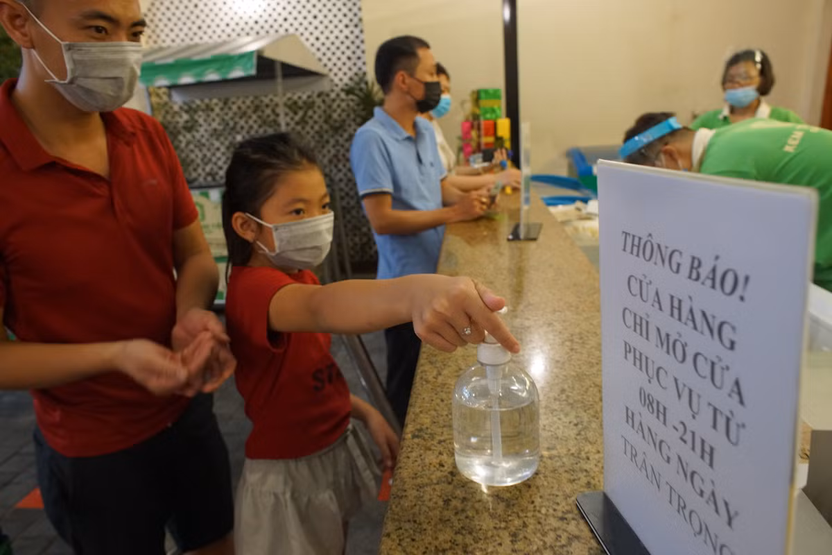 Khách vào mua kem ngoài xếp hàng còn phải khử khuẩn trước khi giao dịch với nhân viên bán hàng.