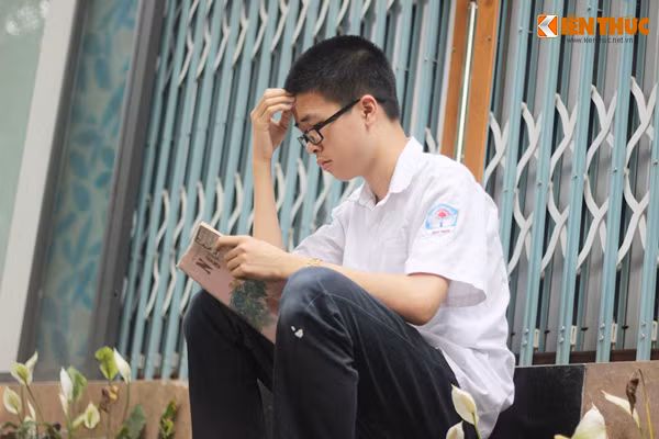 Thí sinh ngồi bên ngoài cổng trường thi tranh thủ ôn lại bài.